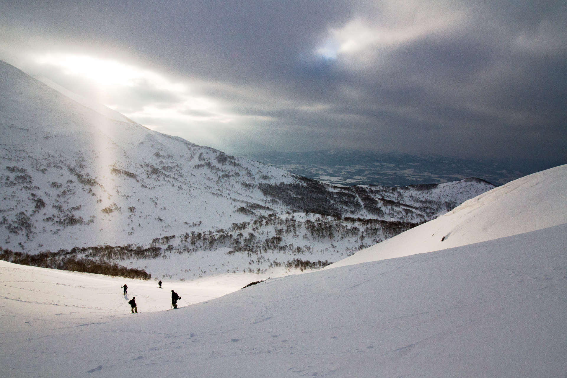 The sun peeks through the clouds in the Niseko backcountry.